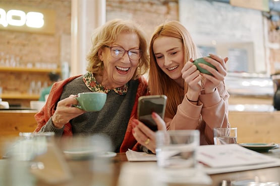 Happy grandmother looking at her phone beside her granddaughter at a café in Hettinger, North Dakota