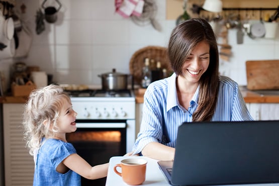 young mother and daughter at kitchen table enjoy business checking accounts on laptop