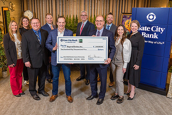 Gate City Bank team members pose with a Beyond Shelter representative holding a big check for affordable housing worth $250K