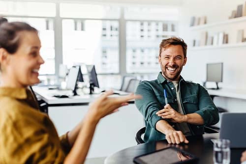 Laughing and relaxed business owner in a button-down shirt, talking at a table with Gate City Investment Services advisors