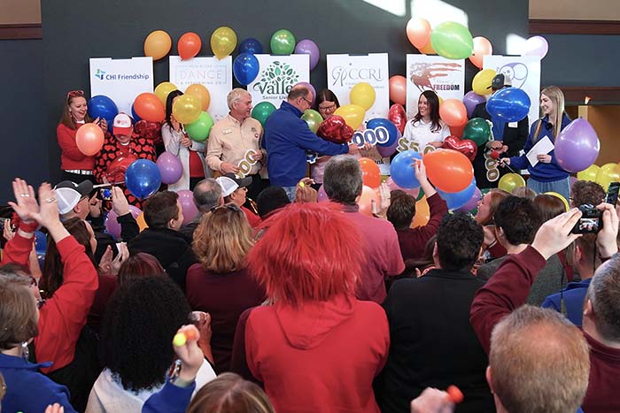 CCRI receives Gate City Bank’s $100,000 Giving Hearts Day donation on stage while balloons fall and people cheer