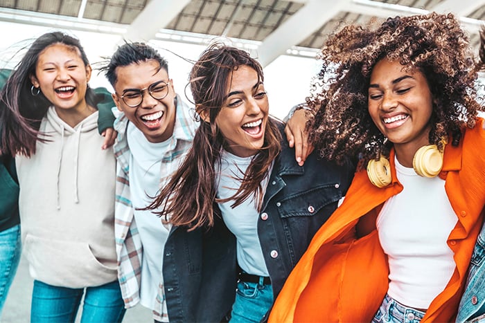 Group of young laughing friends in jeans and hoodies, walking to Gate City Bank in Fargo, ND, to open new checking accounts