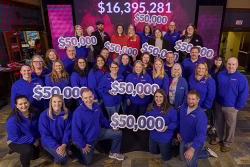 Happy group from Gate City Bank holding “$50,000” signs on Giving Hearts Day