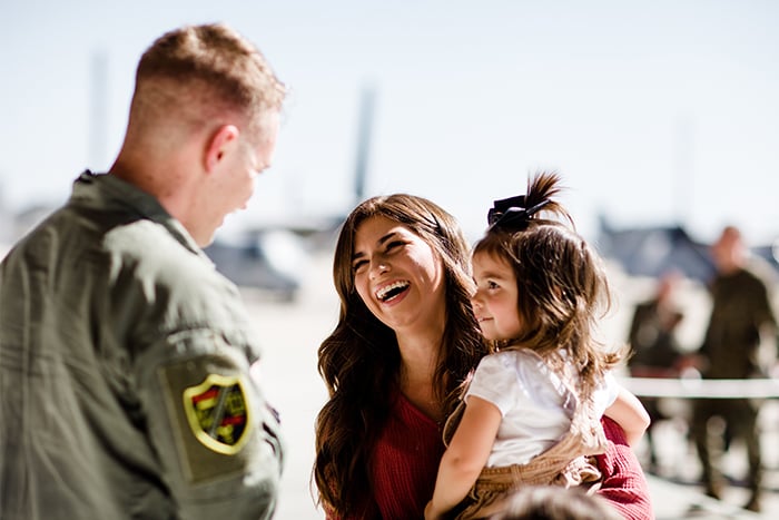 Mother and daughter smile at a father in uniform.