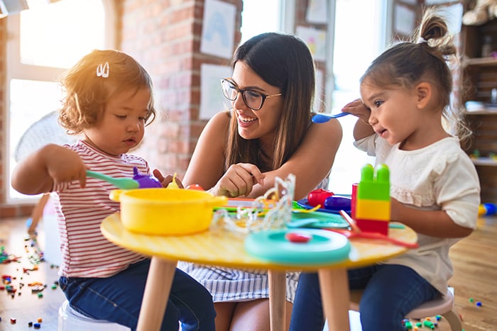 Female daycare provider plays at home with children after receiving approval for BetterLife™ Child Care Business Loan from Gate City Bank