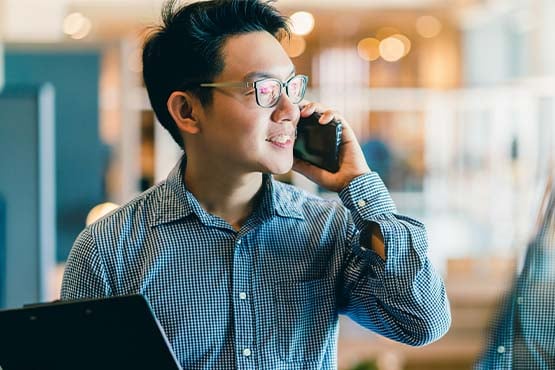 happy male business owner holds phone and tablet after learning how to secure ACH payments