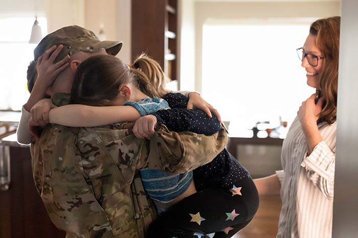 military dad hugs children in their new home purchased with a va loan from gate city bank