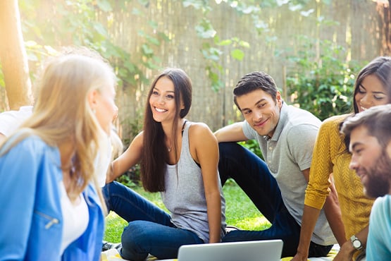 group of friends sits outside with laptop after balancing their checkbooks and finding happiness with gate city bank