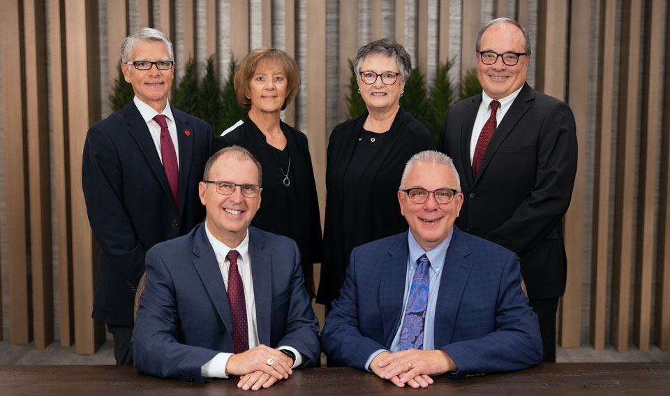Gate City Bank's six board members gather next to a conference room table and smile at the camera