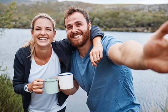 Happy couple smiling for a selfie while camping at the edge of Lake Geneva near Alexandria, Minnesota