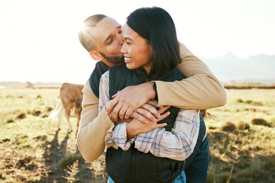 Farmer kisses his laughing wife on the cheek on their family’s cattle ranch near the edge of Dickinson, ND