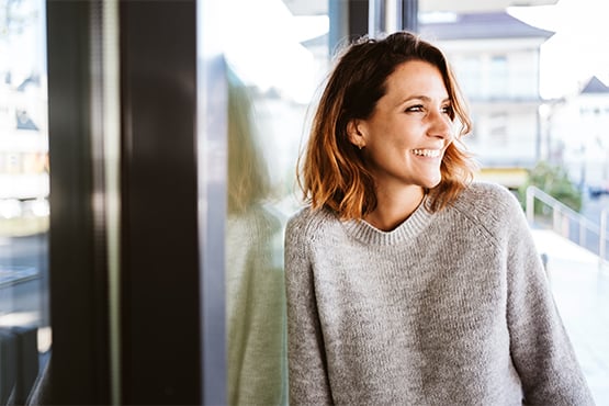 Relaxed young woman in a beige sweater outdoors in North Dakota, getting ready to go to her favorite West Fargo bank