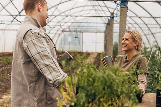 Young couple laughing while drinking coffee in to-go cups at a greenhouse in Mohall, North Dakota