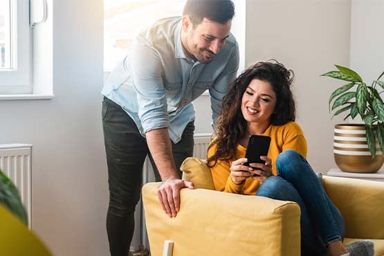 happy man and woman look at phone to access better checking