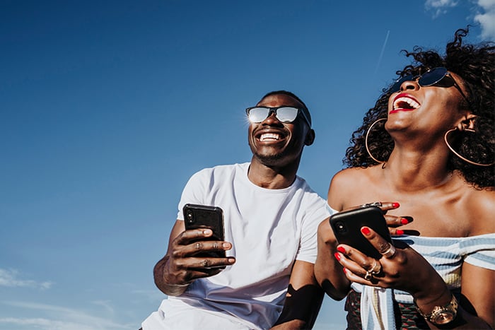 happy young couple holds phones on a sunny day while enjoying debit card controls