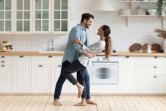 young couple dancing in a white remodeled kitchen after getting a home equity loan