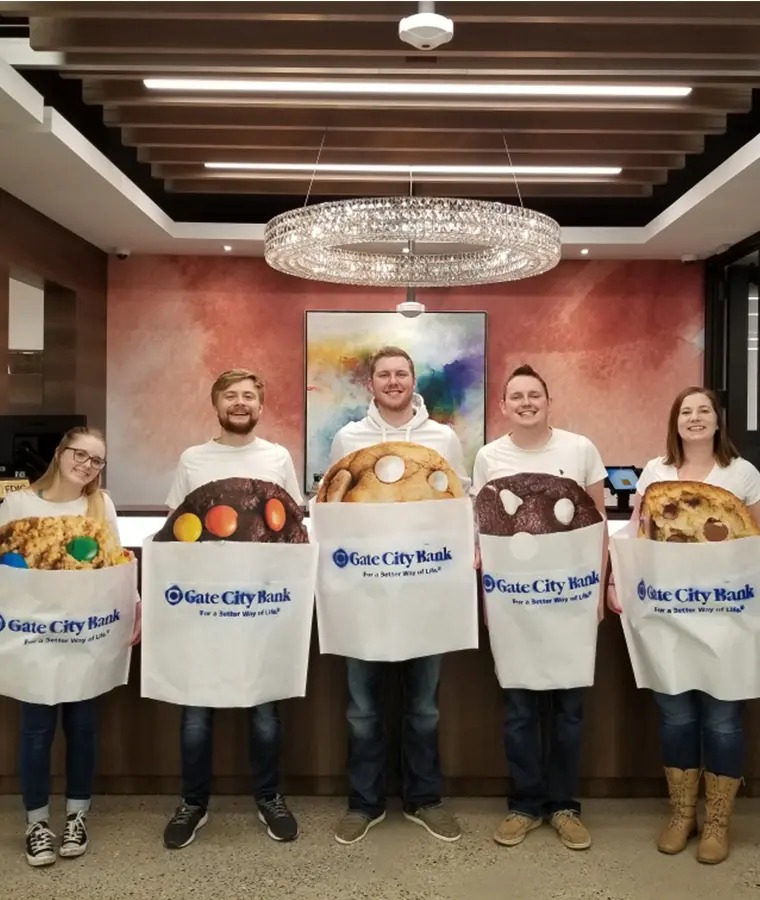2000s color photo of five happy team members lined up and smiling while dressed as Gate City Bank cookies