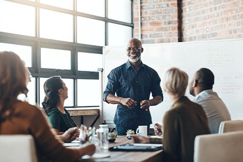 Laid-back businessman with a gray beard leading a meeting inside a brick building in Bismarck, North Dakota